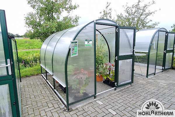 Arcus greenhouse in the garden, in fir green.